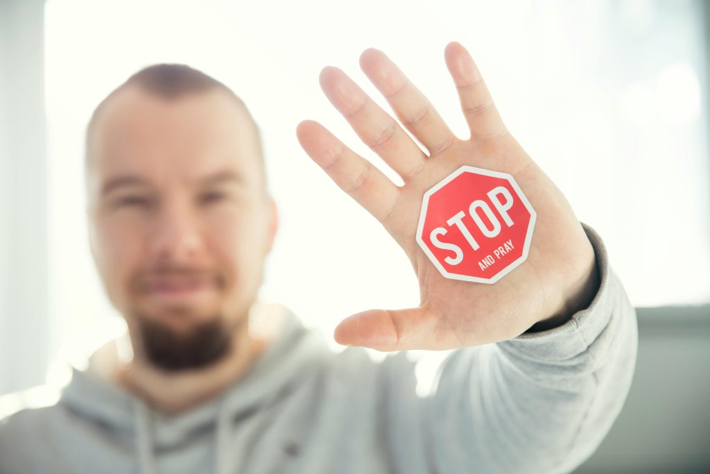 Man holding his hand up with a stop sign in the middle of it